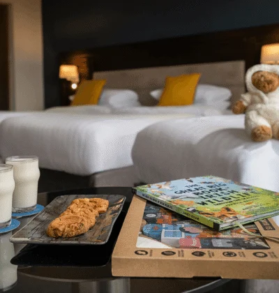 Family-friendly twin room with two plush beds, bedside lamps, teddy, milk, cookies and children’s books on a bedside table, cosy stay
