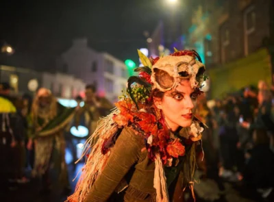Vibrant Halloween festival parade with performers in colourful costumes, capturing cultural vibrancy near local hotel stay.