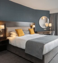 A hotel room with two interconnected beds, modern decor, soft lighting, and large windows offering a scenic view. It's designed for comfort and convenience.