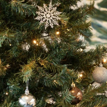 A beautifully decorated event room with elegant Christmas-themed table settings, festive wreaths, and twinkling lights, creating a warm and inviting holiday atmosphere.