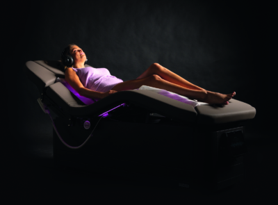 A modern, serene wellness room featuring a specialized therapy bed, soothing blue tones, and subtle lighting, designed for relaxation and rejuvenation in a spa setting.
