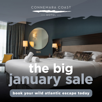 A tranquil ocean view with a clear blue sky, distant mountains, and a rocky coastline. The sun casts a gentle glow on the water, creating a serene atmosphere.