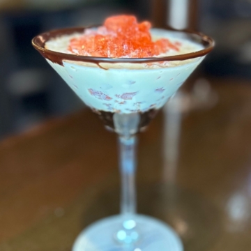 A scenic coastal view with a calm sea, rocky shoreline, rugged hills, and a sunlit sky with fluffy clouds. A serene landscape showcasing the beauty of Connemara, Ireland.