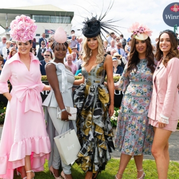 A white bedroom with large windows offering a scenic view of a calm, blue ocean. Cozy sitting area near the window, inviting relaxation. Cozy, elegant ambiance.