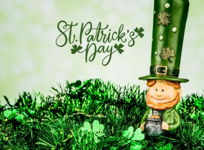 Aerial view of a scenic coastline with a hotel overlooking a rocky shoreline, lush greenery, and an expansive ocean under a partly cloudy sky.