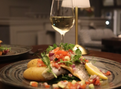 Coastal view from Connemara Coast Hotel: rocky shoreline with seaweed-covered rocks, gentle sea waves, cloudy sky, and rolling hills in the distance. Serene and picturesque scenery.