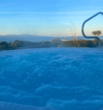 Relaxing hot tub with ocean view, surrounded by lush greenery, perfect for unwinding after a day of adventure.