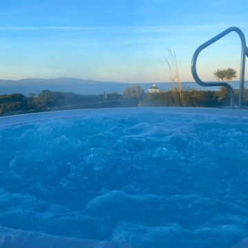 Relaxing hot tub with ocean view, surrounded by lush greenery, perfect for unwinding after a day of adventure.