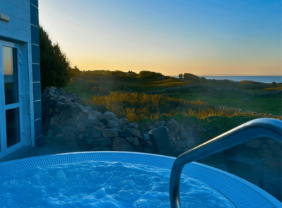 Enjoy serene coastal sunset views from the hotel's outdoor hot tub, offering relaxation and natural beauty.