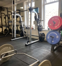 Dumbbells of varying weights neatly organized on a multi-tiered rack in a gym setting.