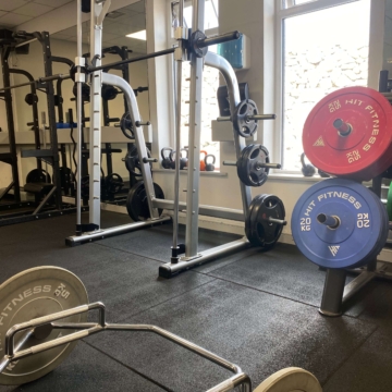 Dumbbells of varying weights neatly organized on a multi-tiered rack in a gym setting.