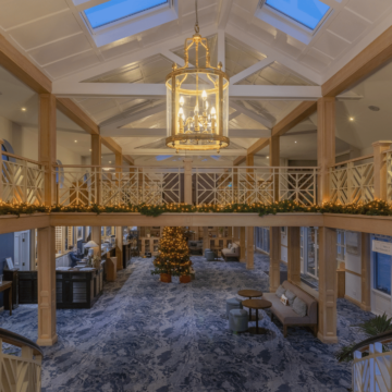 A warmly lit hotel reception area decorated with Christmas trees, festive lights, and garlands, creating a cozy and inviting holiday atmosphere.