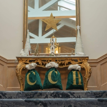Elegant staircase adorned with festive Christmas garlands, baubles, and twinkling lights, creating a warm and inviting holiday atmosphere in a beautifully decorated hotel interior.