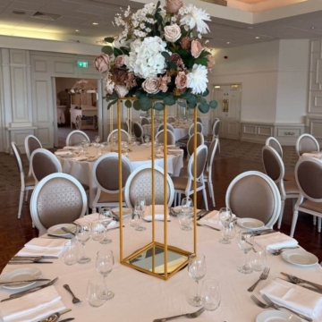 Centrepiece with white candles and various colored flowers displayed elegantly on a table for a wedding event, providing a romantic and festive atmosphere.