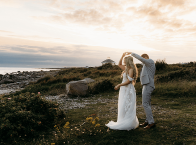 A waterfront wedding ceremony setup with white chairs and floral arrangements, overlooking a scenic view of mountains and a clear sky at the Connemara Coast Hotel.