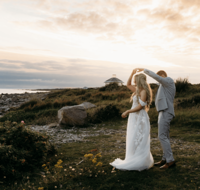 A waterfront wedding ceremony setup with white chairs and floral arrangements, overlooking a scenic view of mountains and a clear sky at the Connemara Coast Hotel.