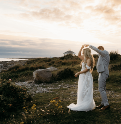 A waterfront wedding ceremony setup with white chairs and floral arrangements, overlooking a scenic view of mountains and a clear sky at the Connemara Coast Hotel.