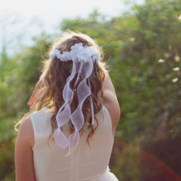 Girl in white dress with floral headpiece enjoying lush garden view at elegant hotel retreat.
