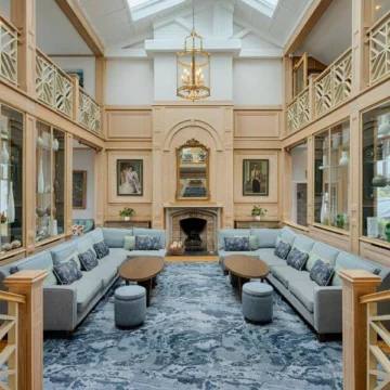 Reception area featuring modern furniture, wooden decor, a fireplace, and contemporary lighting in a welcoming hotel ambiance.