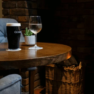 Charming Irish pub with traditional decorations, vintage wooden bar, cozy seating, warm lighting, and array of beverage options. Authentic, inviting ambiance for socializing and relaxation.